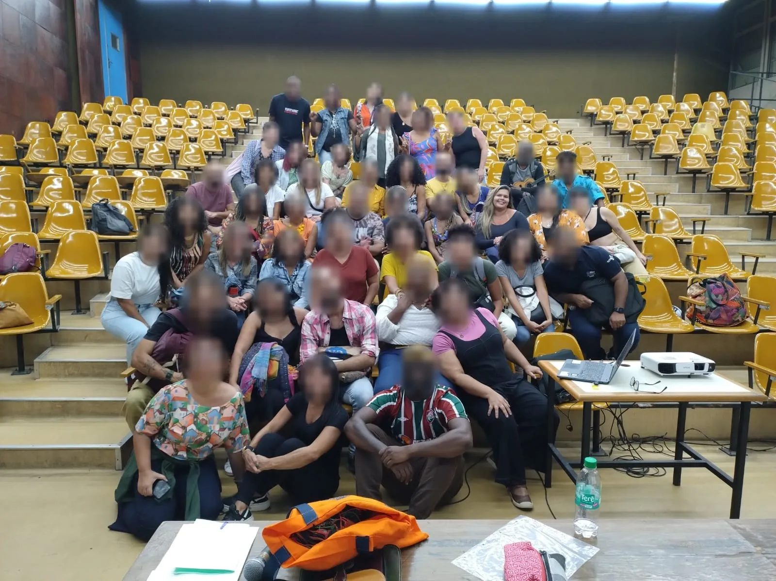 Maria Rejane com a turma do curso de extensão da UERJ sobre racismo e saúde mental, numa arquibancada de auditório; o rosto das outras pessoas está borrado