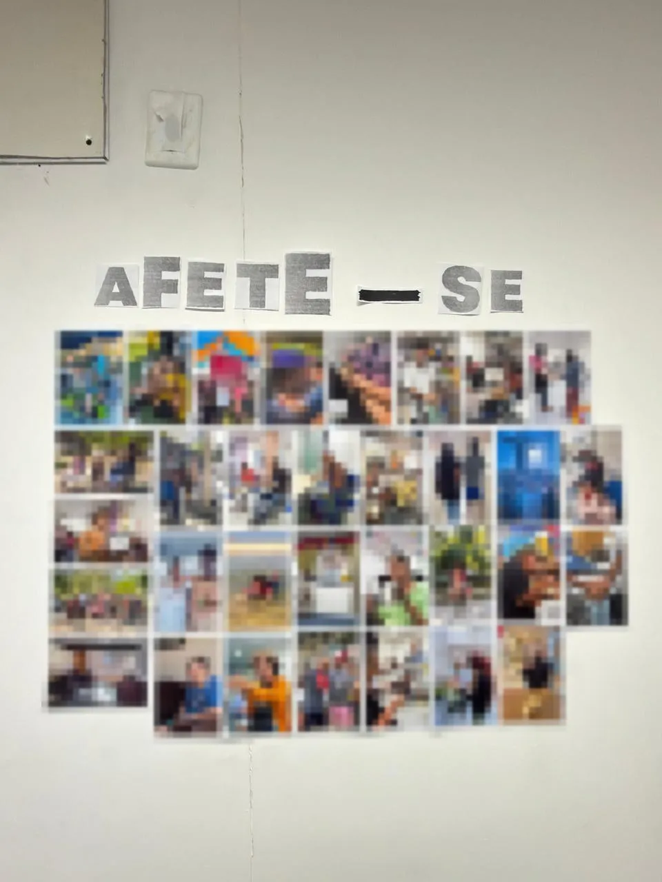 Mural Afete-se, produto técnico do TCC da especialização dela, com dezenas de fotos coladas na parede; as fotos estão borradas