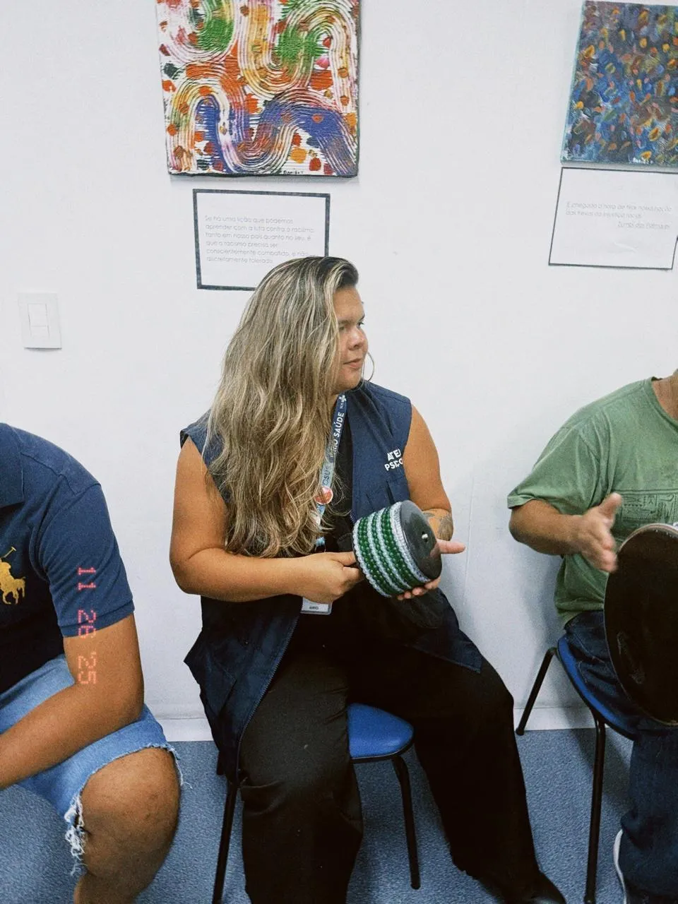 Maria Rejane numa oficina, segurando um instrumento de percussão