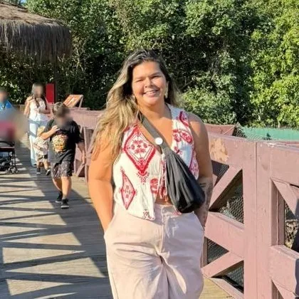 Maria Rejane sorrindo ao ar livre, num dia de sol