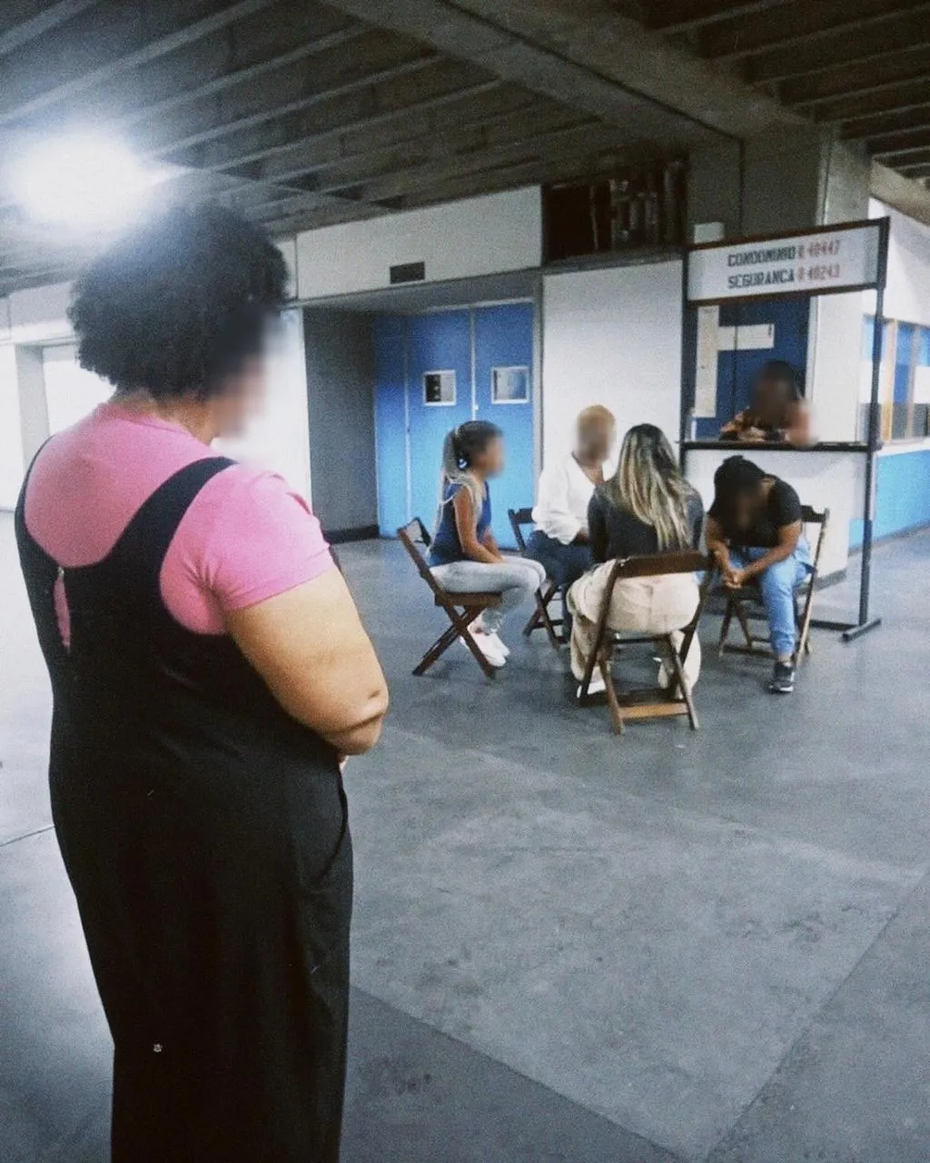 Roda de conversa num corredor, com pessoas sentadas em cadeiras de madeira; os rostos estão borrados